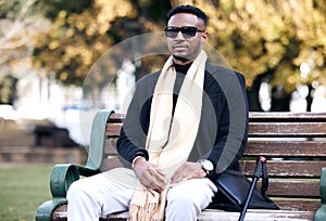 Blind black man, park bench and relax with sunglasses, walking stick or outdoor by trees, peace or thinking. African guy