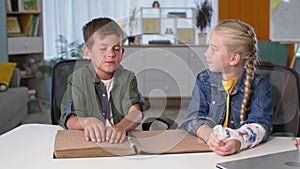 blind boy is reading a book for girl with a plaster cast on hand, visually impaired child is touching the braille with