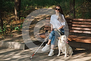 Blind caucasian woman sitting on bench with guide dog.