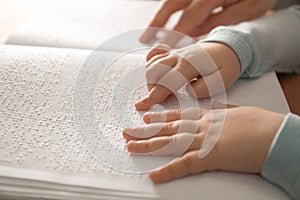 Blind child reading book written in Braille