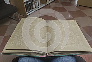 Blind male reading braille language book at library
