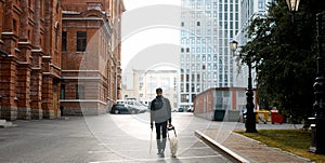 Blind man with cane and guide dog walking on pavement in town