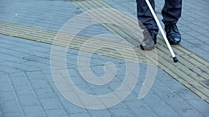 Blind man finds turn on tactile paving using walking stick, urban navigation