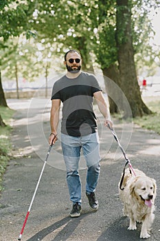 Blind man with guide dog in a summer city