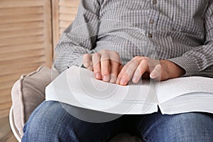 Blind man reading book written in Braille at home