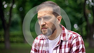 Blind man sitting on bench in park, feeling despair and helplessness, awareness