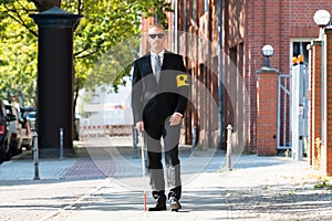 Blind Man Walking On Sidewalk Holding Stick