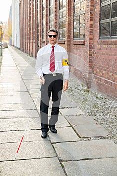 Blind Man Walking On Sidewalk Holding Stick photo