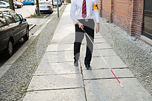 Blind man walking on sidewalk photo