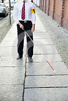 Blind man walking on sidewalk photo
