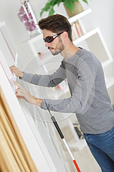 Blind man with white stick and dark glasses at home