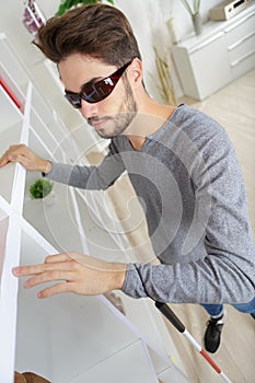 blind man with white stick and dark glasses at home