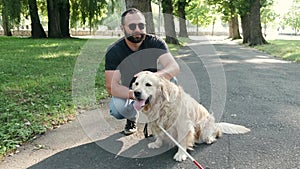 Blind mature man with guide dogs sitting on bench in park