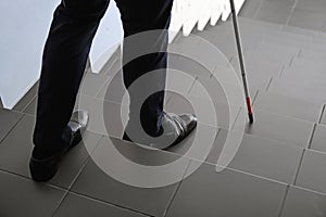 Blind person with long cane going down stairs