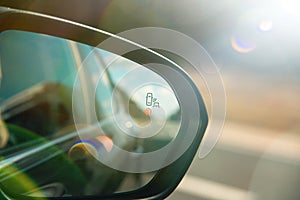 A blind spot monitoring sensor on the side mirror of a modern car