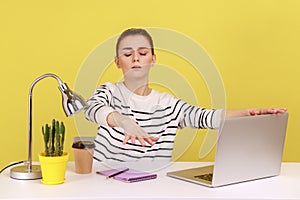 Blind woman employee sitting at workplace with laptop and outstretching hands, touching air.