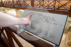 Blind woman reads text on a braille sign for the blind