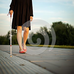 Blind woman walking on city streets, using her white cane