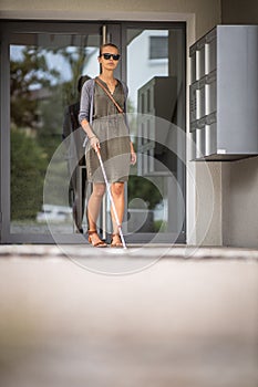 Blind woman walking on city streets, using her white cane