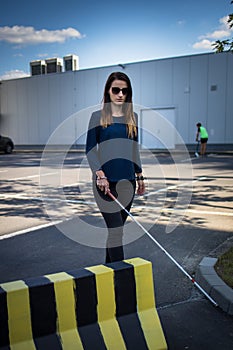 Blind woman walking on city streets, using her white cane