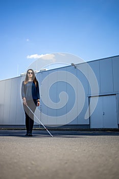 Blind woman walking on city streets, using her white cane