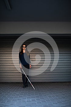 Blind woman walking on city streets, using her white cane