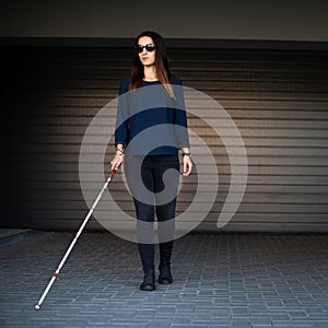 Blind woman walking on city streets, using her white cane