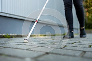 Blind woman walking on city streets, using her white cane