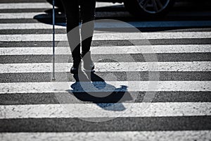 Blind woman walking on city streets, using her white cane