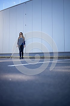 Blind woman walking on city streets, using her white cane