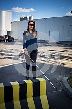 Blind woman walking on city streets, using her white cane