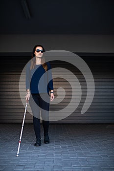 Blind woman walking on city streets, using her white cane