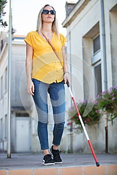 blind woman walking on sidewalk