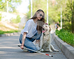 Blind young woman cuddling with guide dog on a walk outdoors.