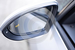 Blind zone monitoring sensor on the side mirror of a modern electric car. System blind spots of the car. Detail of side