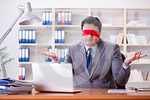 The blindfold businessman sitting at desk in office