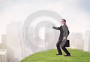 Blindfolded businessman steps on patch of grass