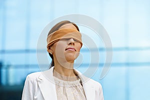 Blindfolded hispanic business woman near office building