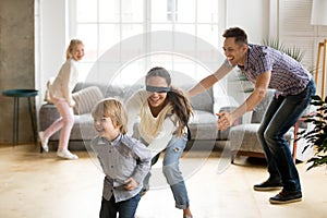 Blindfolded mother catching son playing hide and seek with famil