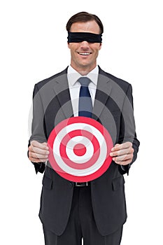 Blindfolded and smiling businessman holding a red target