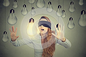 Blindfolded woman walking through lightbulbs searching for bright idea photo