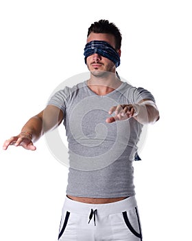 Blindfolded young man feeling his way in the dark