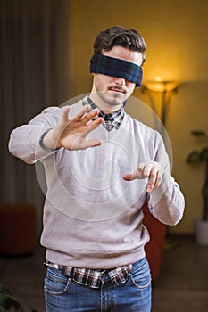 Blindfolded young man at home in living room cannot see