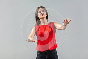 Blindness! Portrait of worry beautiful brunette young woman in red shirt standing with closed eyes and try to touch or find