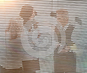 through the blinds. office staff discuss working documents. communication of partners against the background of sunset