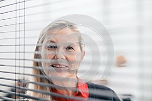 Through the blinds. successful businesswoman looking through office window