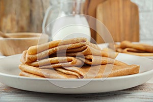 Blini, blintzes, russian crepes stacked on plate over rustic composition background photo