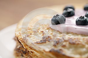 Blini or crepes with yogurt and blueberries closeup