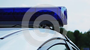 Blinking blue flashing lights during the day. Police patrol car. Close up