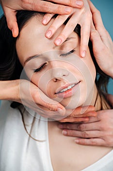 Blissed out woman having pleasurable face massage from multiple hands